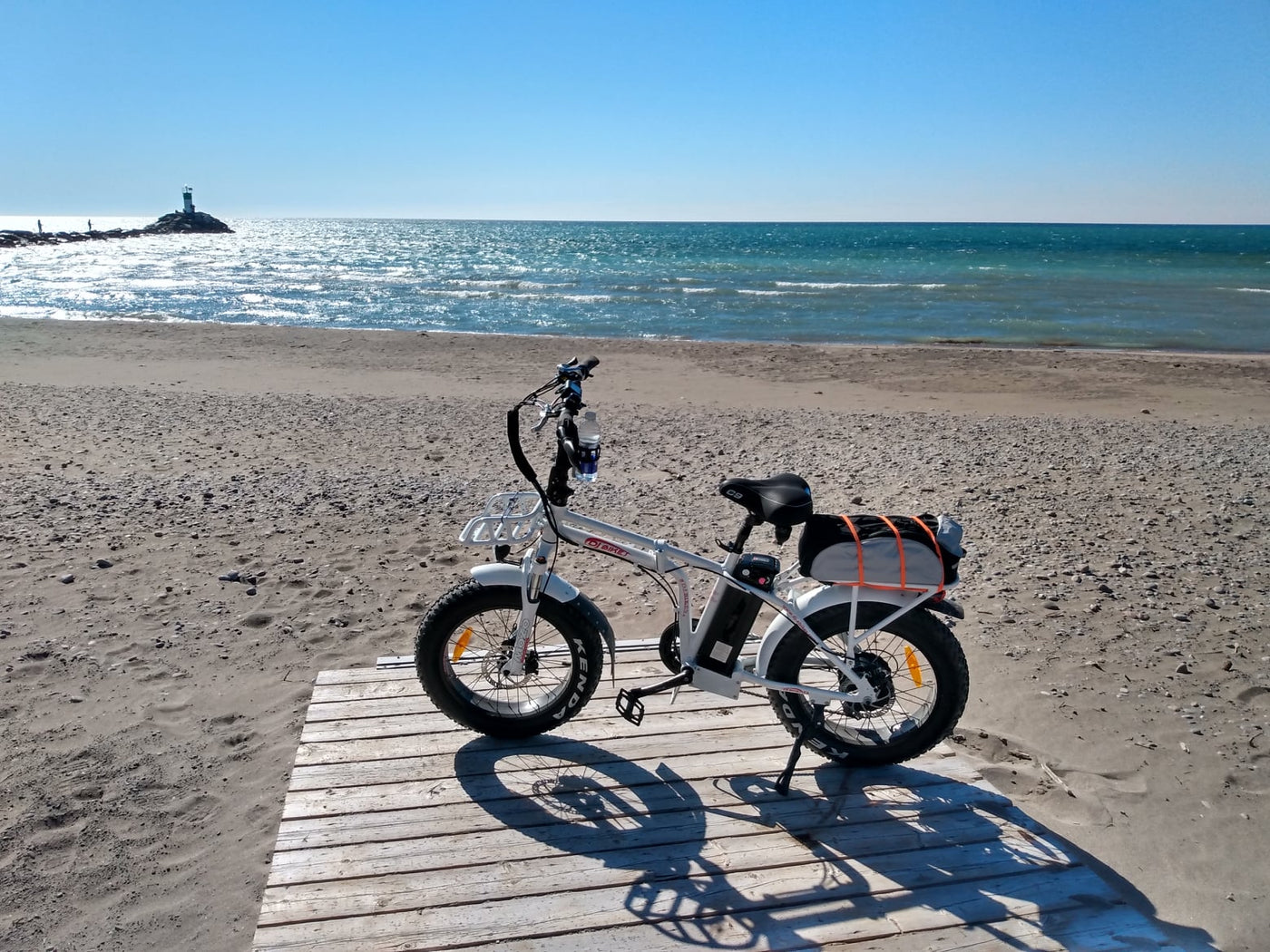 A DJ Folding Bike fat tire e-bike equipped with trunk bag on a sandy beach