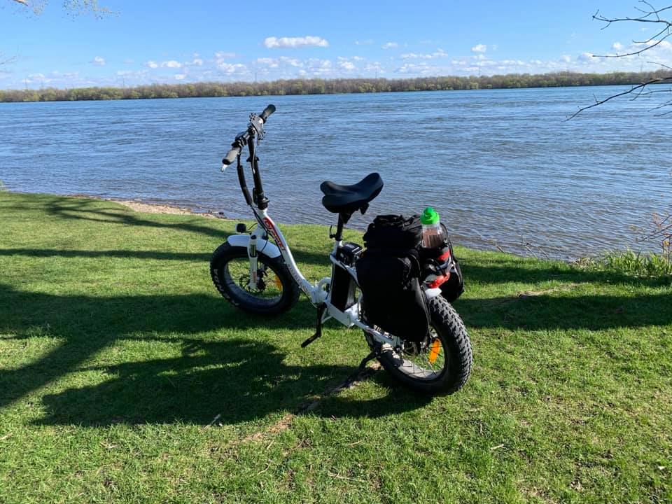 A DJ Folding Step Through fat tire e-bike equipped with pannier bag in front of a river